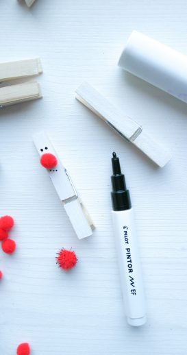 Auf der weißen Wäscheklammern wird eine rote Nase angeklebt und Augen und Mund zeichnen mit einem schwarzen Kreativmarker.