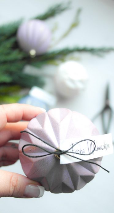 Weihnachtskugel in Hand mit Weihnachtsgruß